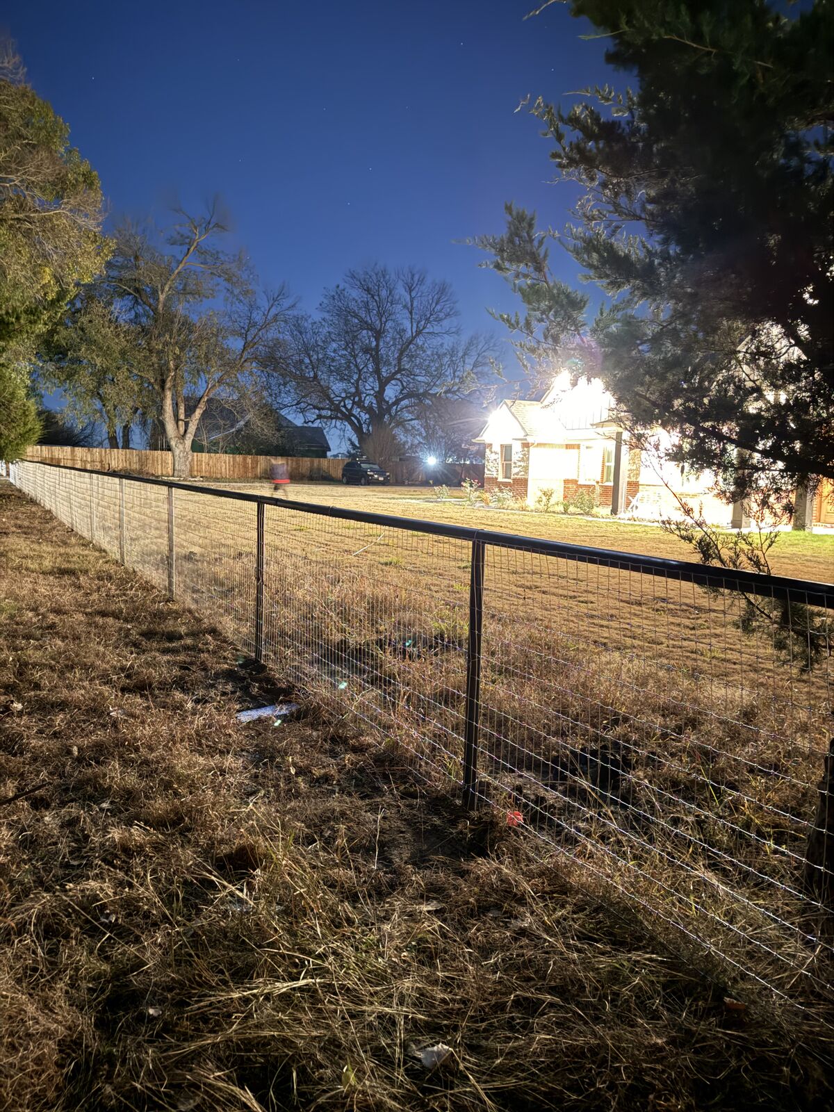 Newly set pipe and wire fence photographed at dusk