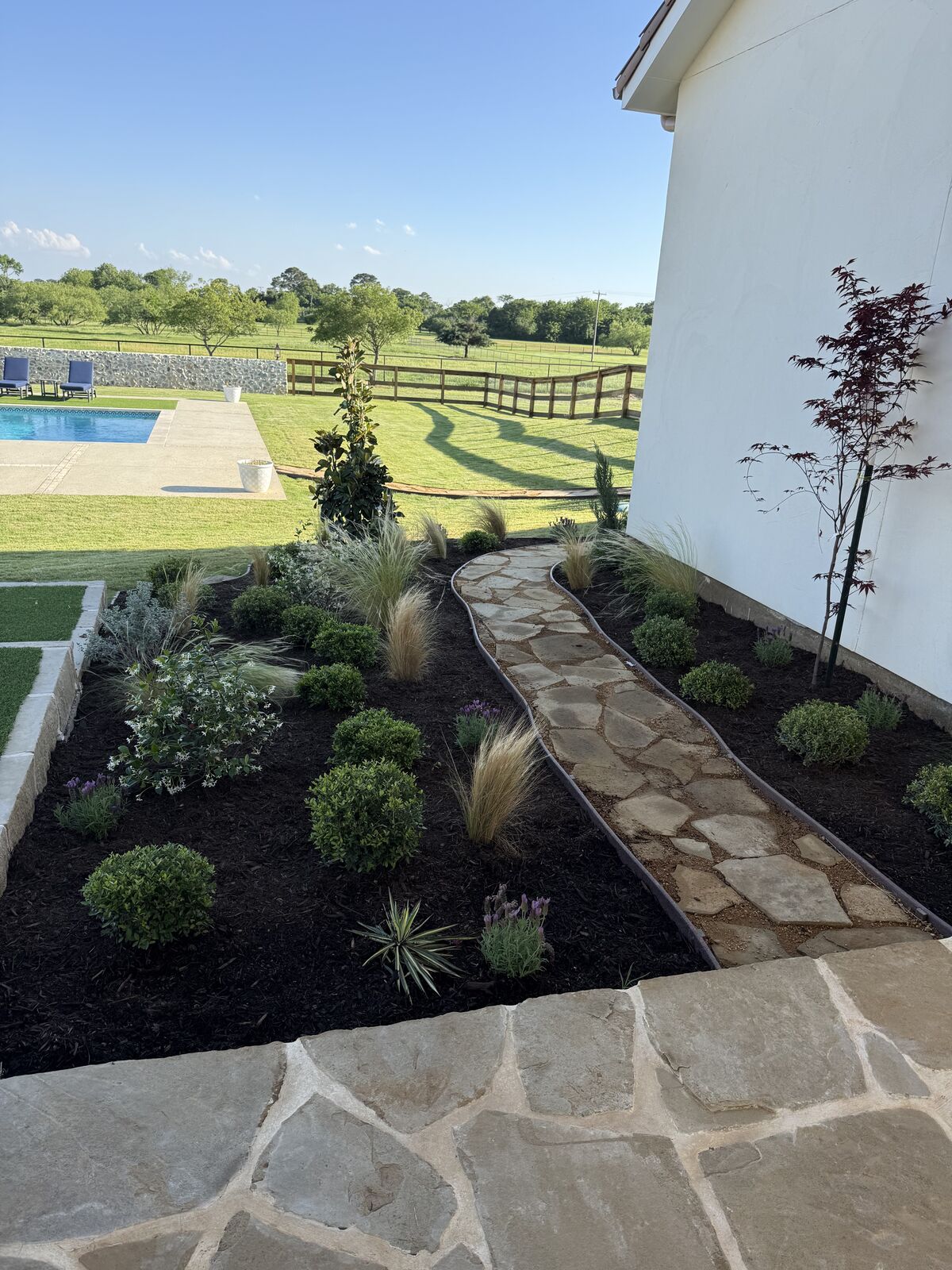 Flagstone walkway and fresh landscape beds beside a ranch home